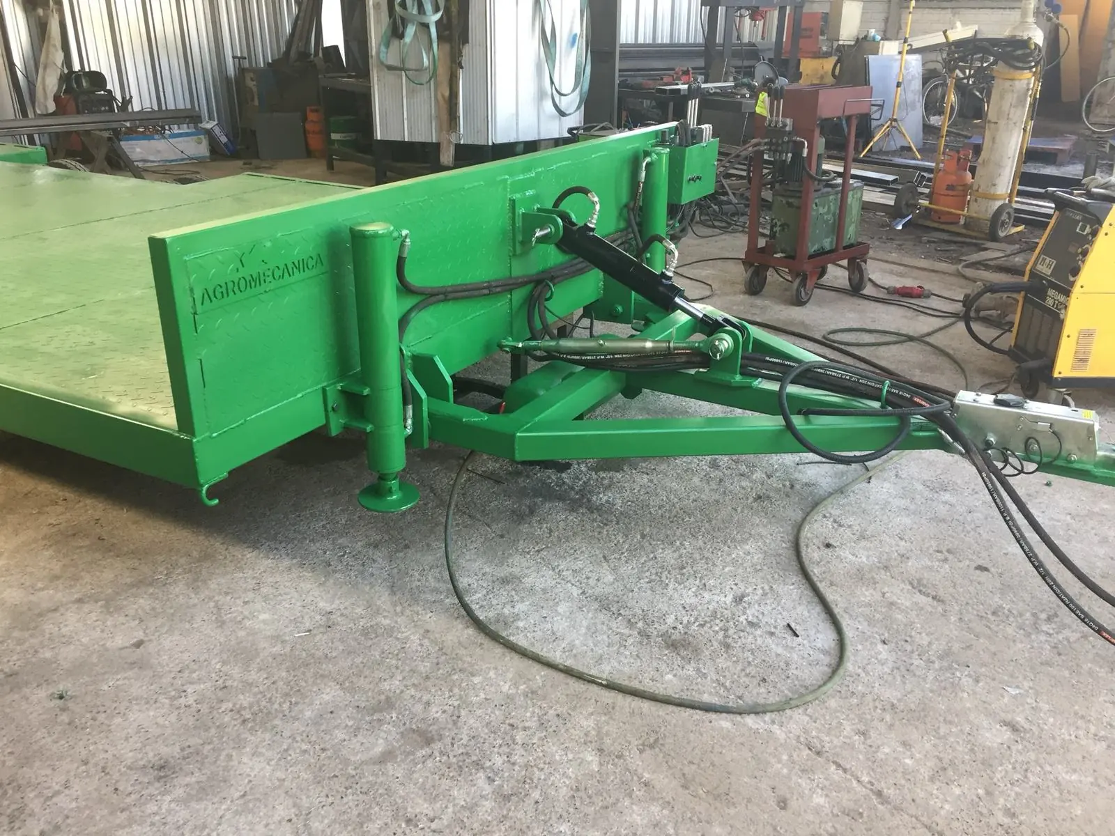 Carro plataforma verde recién armado dentro de la maestranza, entre máquinas herramienta.