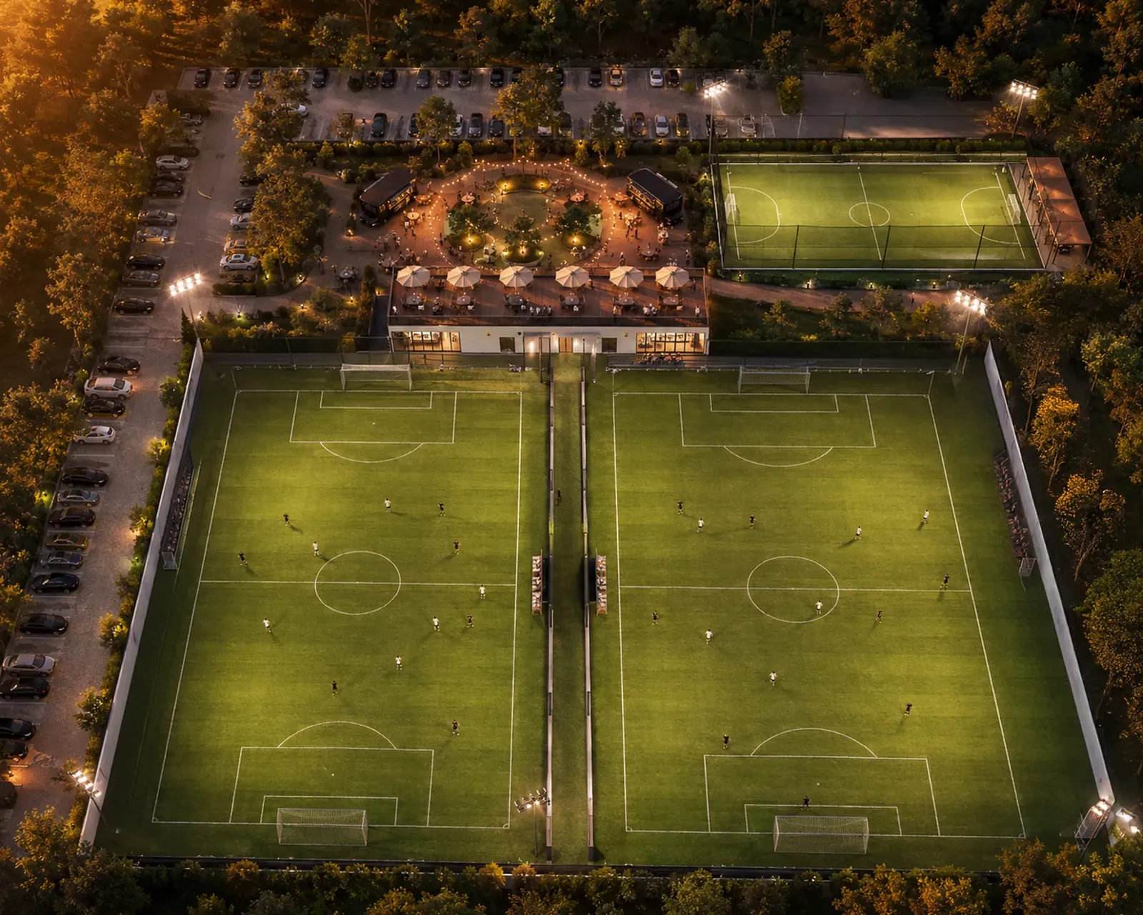 Vista aérea nocturna del complejo: dos canchas iluminadas y la terraza.