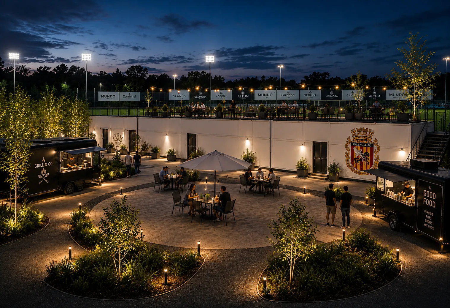 Zona social con foodtrucks y mesas, de noche.