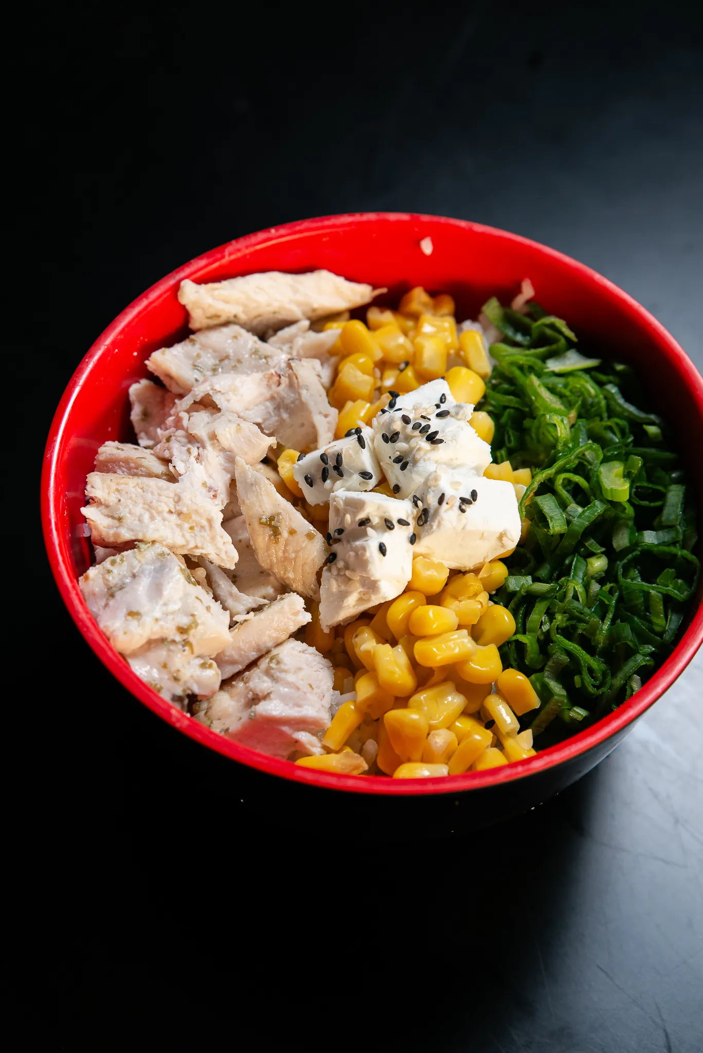 Bowl de arroz, pollo y verduras servido en loza roja.